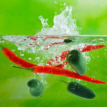 Dynamische splash foto van rode en groene pepers