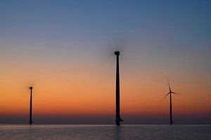 Windturbinen in einem Offshore-Windpark produzieren Strom bei Sonnenuntergang