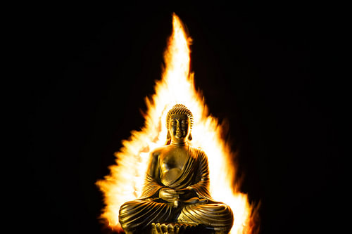 Buddha statue surrounded by flames radiating warmth and protection