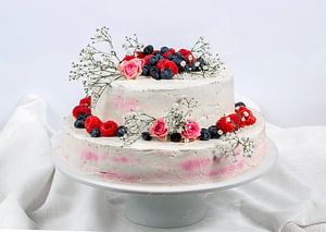 sommerliche frische zweistöckige Hochzeitstorte mit Beeren und Blumen verzierte festliche Sahnetorte