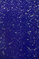 Abstracte weergave van waterdruppels op het raam met een blauwe achtergrond