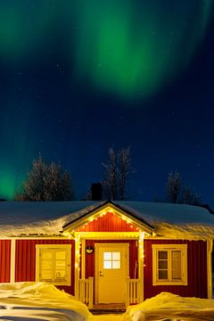 Aurores boréales au-dessus d'un chalet en Laponie suédoise sur Kelly De Preter