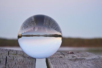 Glaskugel auf einem Steg der in einen See reicht von Martin Köbsch