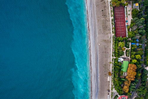 Multicolored trees and stadium. Hotels among the green park on the seafront with turquoise water and