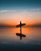 Silhouet van een surfer tijdens zonsondergang