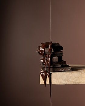 Smeltende pure chocolade druppelend van houten plank