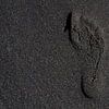 Voetafdruk in zwart zand van Stijn Cleynhens