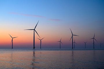 Windturbinen in einem Offshore-Windpark produzieren Strom bei Sonnenuntergang