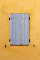 Blue shutters on an ochre-coloured wall in the village of Villedieu in France