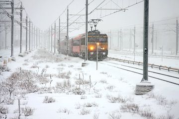 Rijdende trein in de sneeuw bij Amsterdam in Nederland van Eye on You