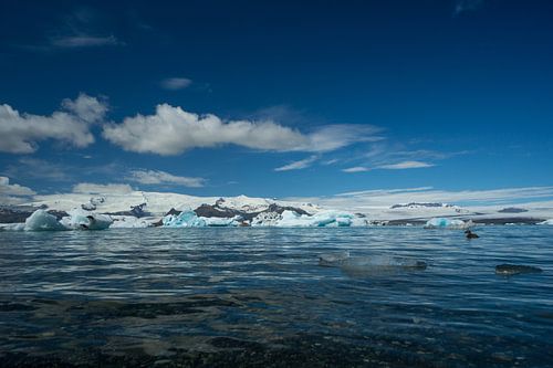 Islande - Eau claire d'un lac glaciaire avec un bateau loin entre les glaces