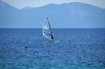 windsurfer wit met doorzichtig zeil surfend in het blauw landschap