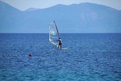 windsurfer wit met doorzichtig zeil surfend in het blauw landschap