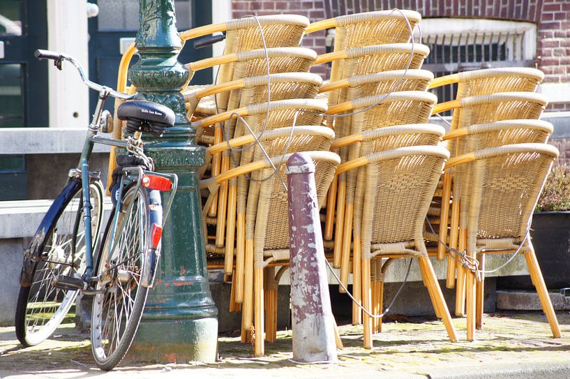 Bicycle against pole with stacked chairs by Marion Hesseling