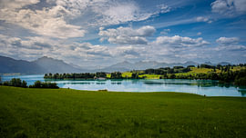 Forggensee beneath a vast cloudy sky with a view of the Alps by ManfredFotos