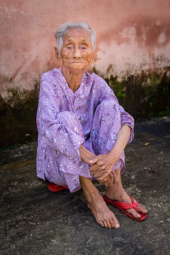 Ältere blinde Frau sitzt auf ihrem Pantoffel in Hoi An
