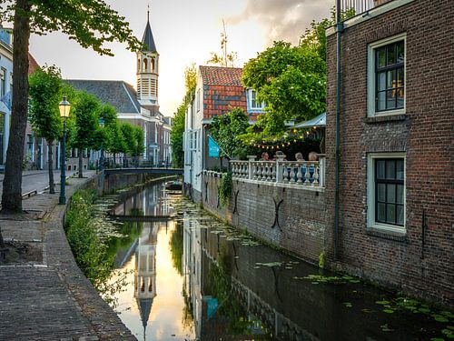 Church tower in Amersfoort behind a canal with people on a terrace
