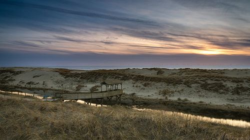 De zee naderen. Steiger met overkapping aan de kust bij Petten tijdens kleurrijke zonsondergang