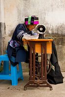 Vrouw in traditionele kleding uit China naait kleding op de naaimachine