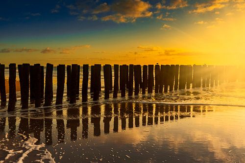 Dutch clouds and typical breakwater of wooden poles along the coast of Zeeland