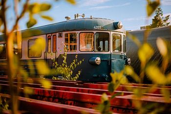 Autorail bleu entre rails rouges – photographie ferroviaire à l’heure dorée