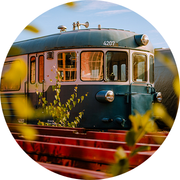 Blauw vintage treinstel tussen rode rails – spoorkunst in golden hour