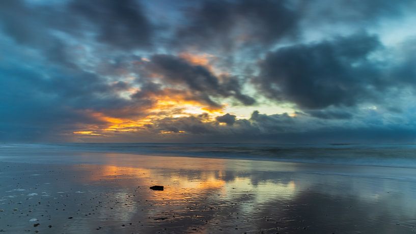 Dreigende wolken en ondergaande zon boven de Noordzee aan de kust van Noord-Holland van Bram Lubbers