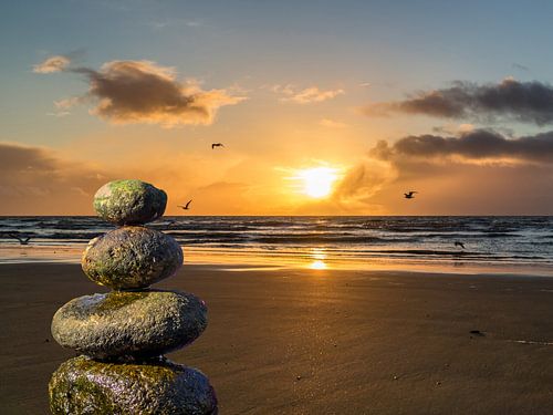 Stenen balanceren op het strand met zonsondergang