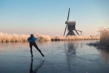 Le patinage sur glace dépasse les roseaux givrés et un moulin à vent