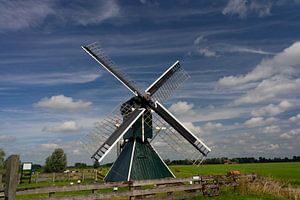 Hollandse molen tegen een heldere, blauwe lucht met witte wolken.