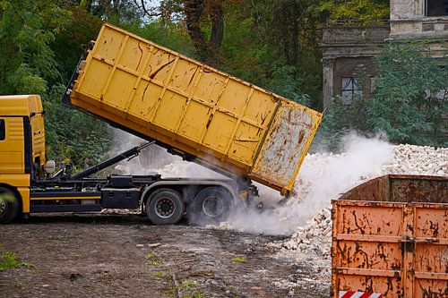 Vrachtwagen op een bouwplaats dumpt een container met stenen