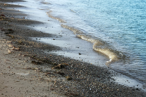 Ruhige Wellen am Strand mit Sand und Kieselsteinen an der Ostsee in Norddeutschland, Kopierraum, aus