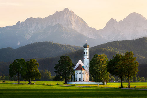 St Coloman bathed in warm light against the backdrop of the Alps
