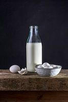 Stilleven van fles melk, eieren op een bankje van oude houten balken