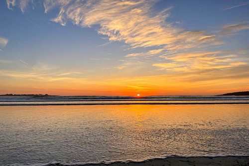 Golden clouds forming over the shallow waters near the shore