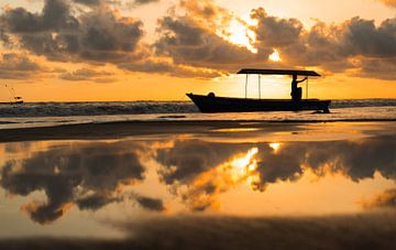 Zonsondergang op het strand met bootje van Iris Hagemans