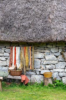 Naturally dyed wool is drying against the wall of a stone house.