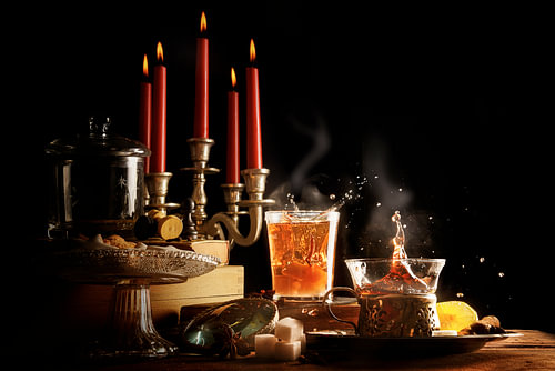 heißer Tee mit Spritzern und Dampf, Kerzen und Süßigkeiten machen die dunkle Winterzeit gemütlich, r