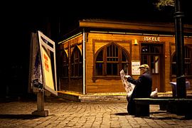 Un homme lit son journal sur un banc, le soir à Istanbul. sur Eyesmile Photography