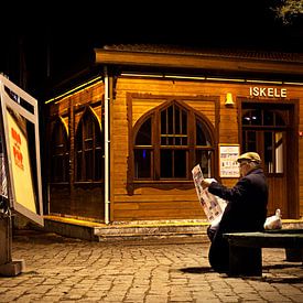 Man leest zijn krant op een bankje, in de avond in Istanbul. van Eyesmile Photography