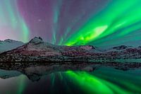 Northern Lights or Aurora Borealis over  a lake with snowy winter mountains
