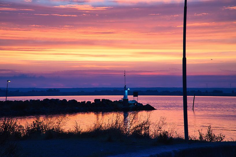 Lighthouse in the harbour at sunset by Martin Köbsch
