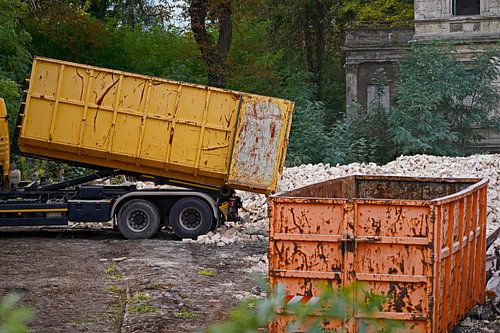 Vrachtwagen op een bouwplaats dumpt een container met stenen