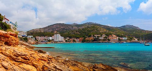 Zonnige dag op het rotsstrand met blauw water