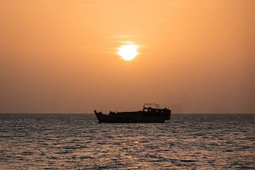 Tansanisches Boot segelt bei Sonnenuntergang friedlich an der Küste von Stone Town entlang von Michiel Ton