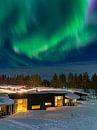 Aurora over huts in winter in Kuusamo, Finland by Rico Ködder thumbnail