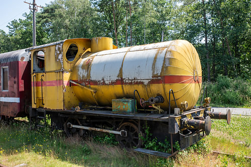 Rostiger gelber Zugtankwagen – Verlassener Oldtimer-Waggon auf einer überwucherten Bahnstrecke von ChrisWillemsen