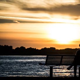 zitten bij zonsondergang van Rick Koppelaar