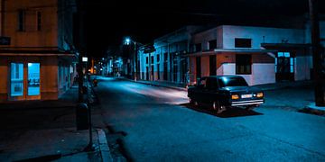 Een oude auto rijdt 's nachts door een donkere straat in Cuba van MICHEL WETTSTEIN