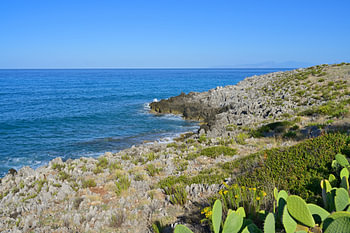 A rocky Mediterranean coastline with clear, blue sea and sky